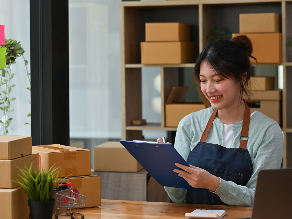Small business owner checking online orders on a clipboard