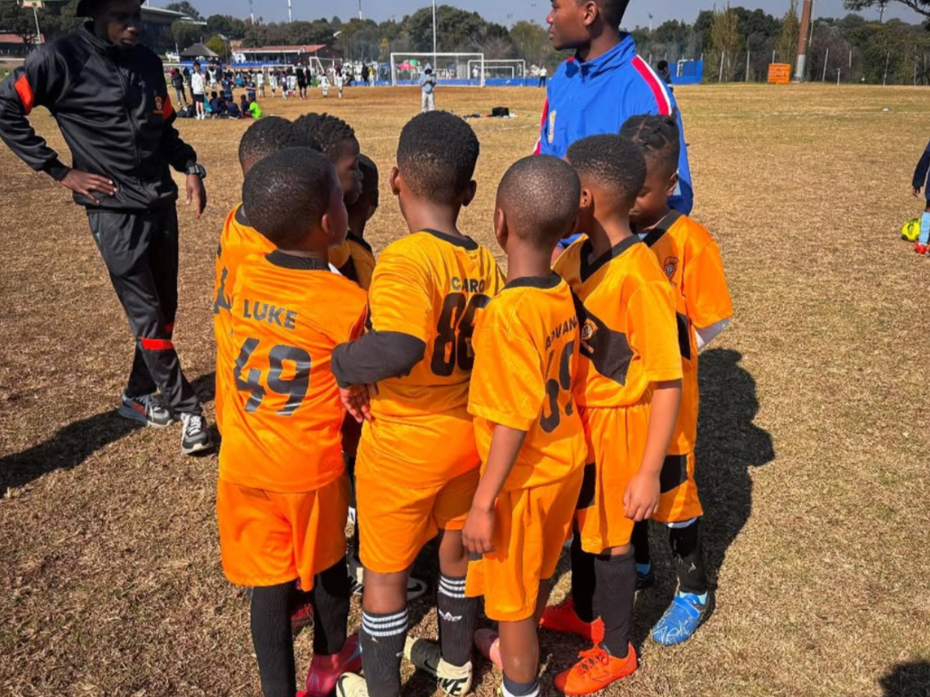 Young football players gathered with coaches on a sports field